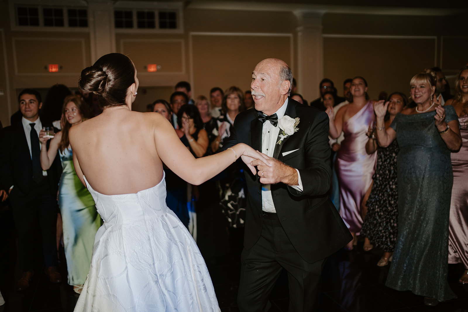 Bride and her father smiling happily during their father-daughter dance on the reception dance floor.